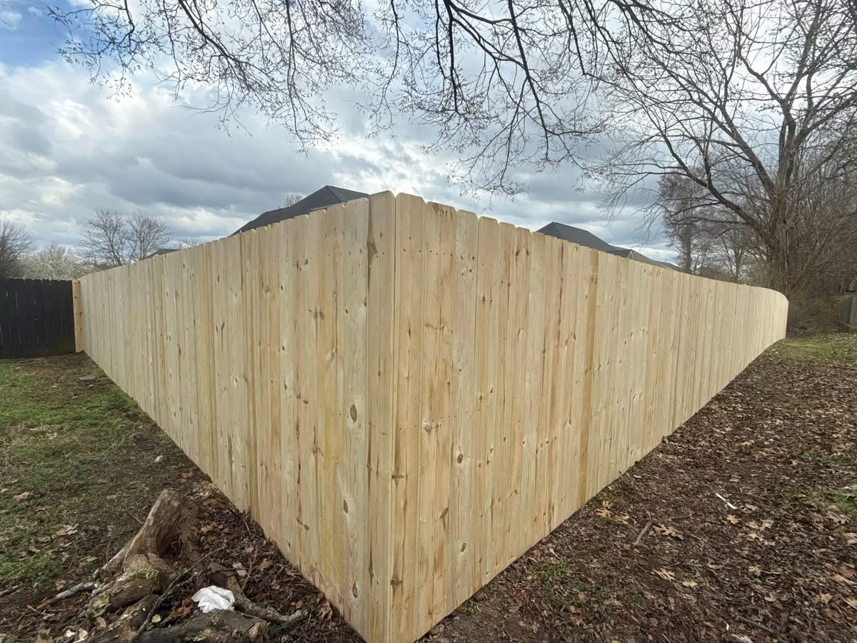 New pressure-treated privacy fence wrapping a backyard corner