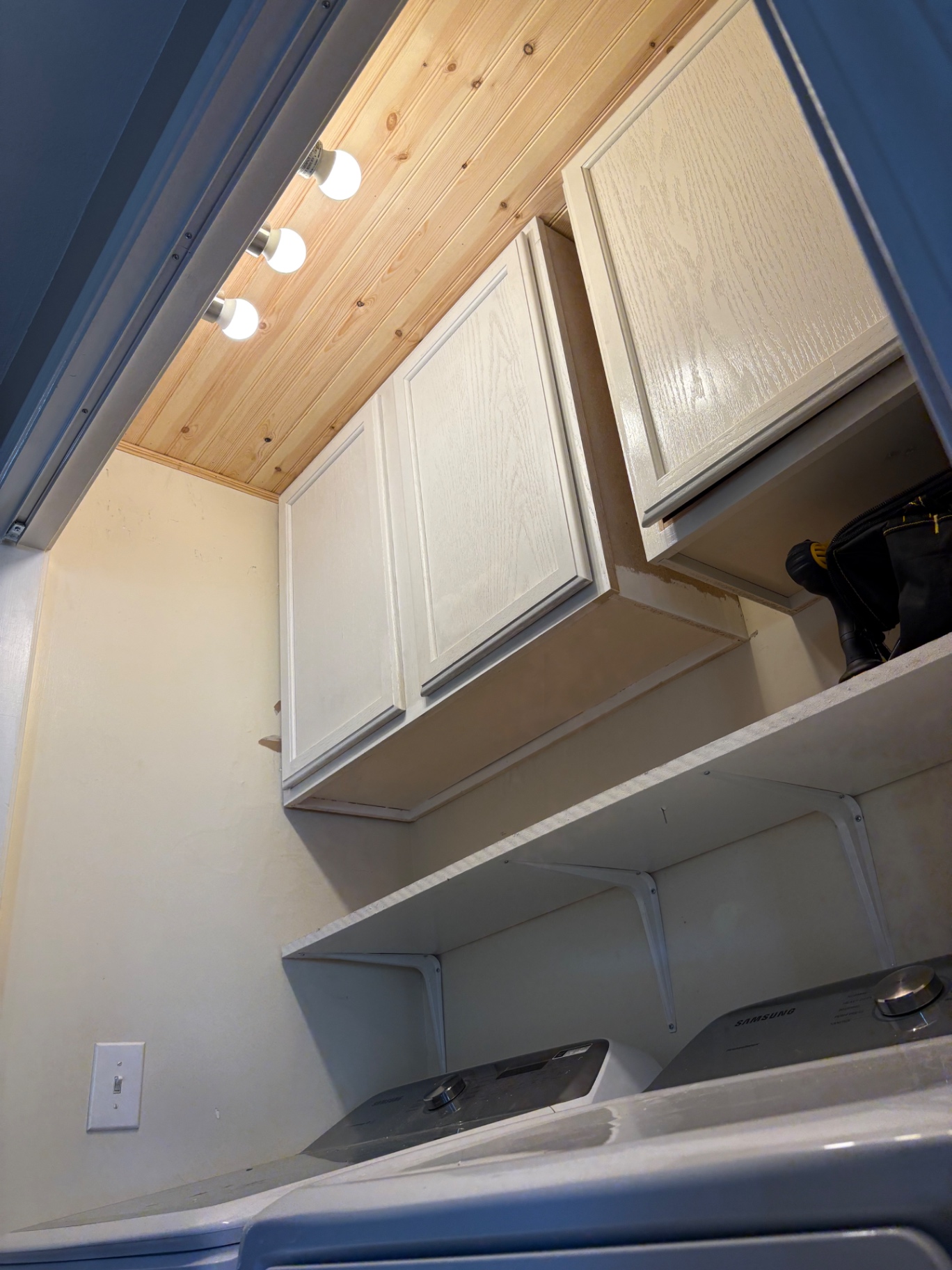 Laundry room with installed cabinets, shelving and pine ceiling